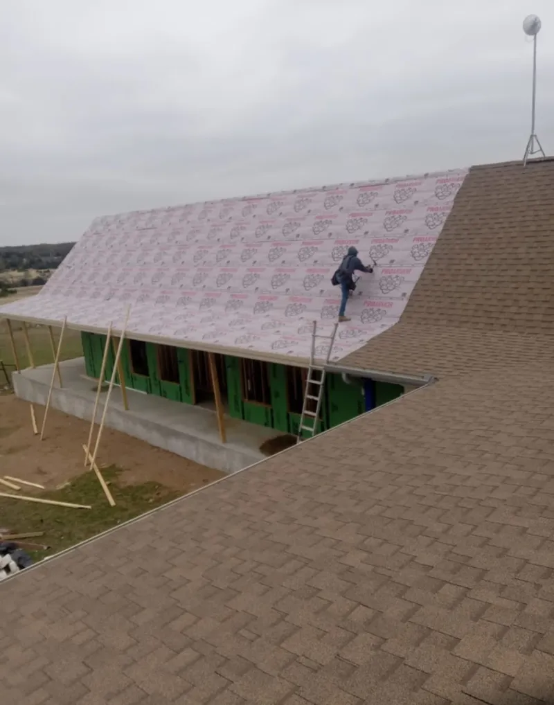 Worker preparing underlayment for a metal roof installation in Preston